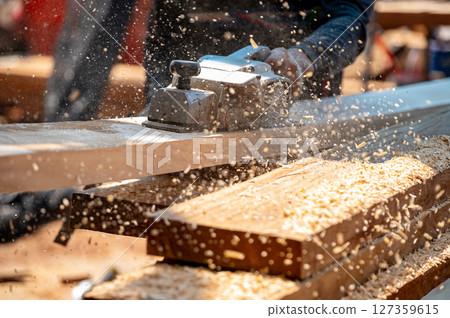 Male carpenter hand using an electric planer on wooden plank in workshop Male carpenter hand using an electric planer on wooden plank in workshop 127359615
