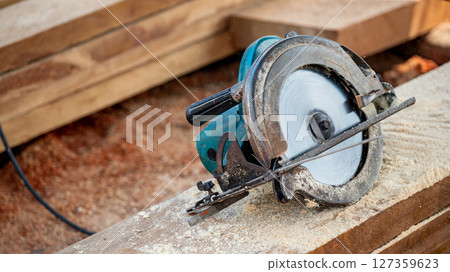 Electric circular saw on timber stack in a wood workshop Electric circular saw on timber stack in a wood workshop 127359623
