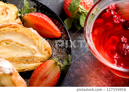 Sliced rolls with custard. The dessert is decorated with fresh strawberries. Sliced rolls with custard. The dessert is decorated with fresh strawberries. 127359958