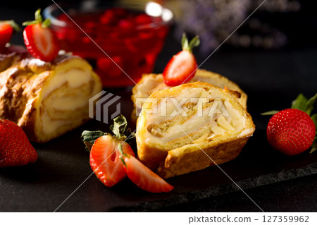 Sliced rolls with custard. The dessert is decorated with fresh strawberries. 127359962