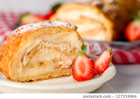 Sliced rolls with custard. The dessert is decorated with fresh strawberries. Sliced rolls with custard. The dessert is decorated with fresh strawberries. 127359964