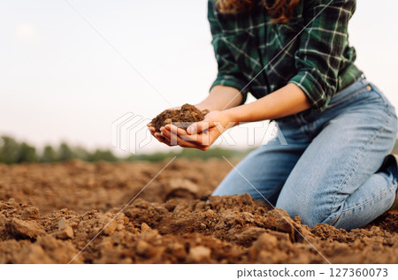 Close-up of woman farmer's hands with black soil in agricultural field. Ecology, gardening concept. 127360073