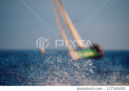 Sailing regatta in the Gulf of Finland at sunset, sailing yacht competing in a race, splashing water from under the boat, teamwork, board the boat 127360085