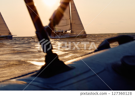 Sailing regatta in the Gulf of Finland at sunset, two sailing yachts competing in a race, splashing water from under the boats, teamwork, board the boat Sailing regatta in the Gulf of Finland at sunset, two sailing yachts competing in a race, splashing water from under the boats, teamwork, board the boat 127360128