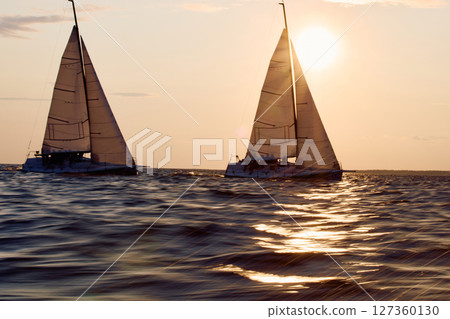 Sailing regatta in the Gulf of Finland at sunset, two sailing yachts competing in a race, splashing water from under the boats, teamwork, board the boat 127360130