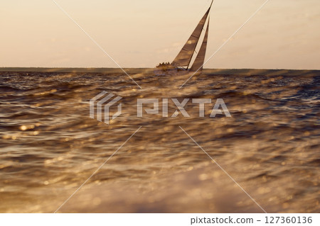 Sailing regatta in the Gulf of Finland at sunset, sailing yacht competing in a race, splashing water from under the boat, teamwork, board the boat 127360136