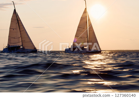 Sailing regatta in the Gulf of Finland at sunset, two sailing yachts competing in a race, splashing water from under the boats, teamwork, board the boat 127360140