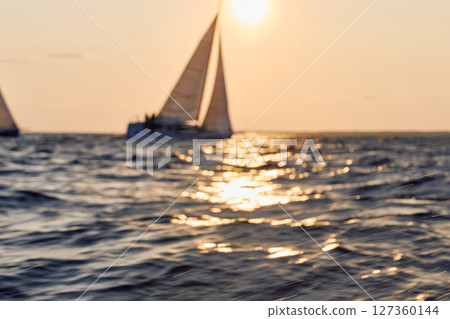 Sailing regatta in the Gulf of Finland at sunset, sailing yacht competing in a race, splashing water from under the boat, teamwork, board the boat Sailing regatta in the Gulf of Finland at sunset, sailing yacht competing in a race, splashing water from under the boat, teamwork, board the boat 127360144