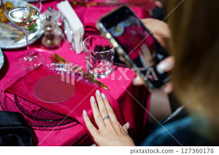 A woman's hand with a new ring. the background of a table with a red tablecloth A woman's hand with a new ring. the background of a table with a red tablecloth 127360178