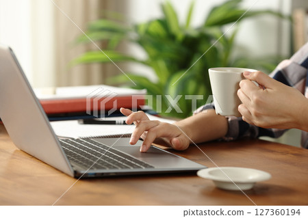 Student hands using laptop drinking coffee on wooden table 127360194
