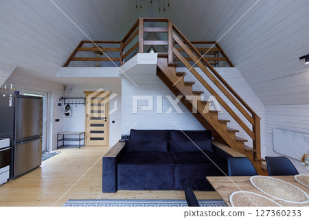 Charming and Cozy Wooden Cabin Interior Featuring Loft Space, Open-Plan Living Area, Stylish Furniture, and Soft Natural Light Enhancing the Inviting Atmosphere of the Home Charming and Cozy Wooden Cabin Interior Featuring Loft Space, Open-Plan Living Area, Stylish Furniture, and Soft Natural Light Enhancing the Inviting Atmosphere of the Home 127360233