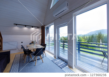 Cozy Modern Dining Space with Scenic Views in a Charming Mountain Getaway Featuring Large Windows to Bring the Outdoors In and Inviting Interior Decor for a Relaxing Atmosphere Cozy Modern Dining Space with Scenic Views in a Charming Mountain Getaway Featuring Large Windows to Bring the Outdoors In and Inviting Interior Decor for a Relaxing Atmosphere 127360236