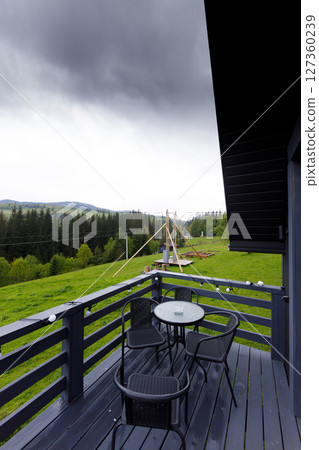 Scenic View from a Cozy Balcony Overlooking Lush Green Fields and Darkening Clouds, Perfect for a Relaxing Getaway in Nature's Embrace Amidst the Mountains Scenic View from a Cozy Balcony Overlooking Lush Green Fields and Darkening Clouds, Perfect for a Relaxing Getaway in Nature's Embrace Amidst the Mountains 127360239