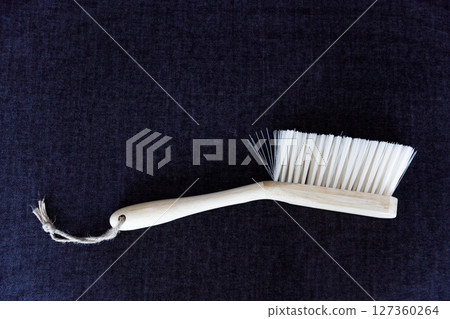A Simple Yet Elegant Wooden Brush with Synthetic Bristles Set Against a Dark Background, Perfect for Cleaning Tasks in Various Environments and Settings 127360264