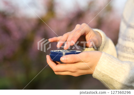Woman hands holding moisturizer jar in a field 127360296