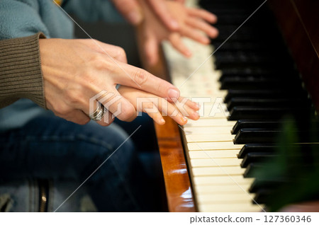 Piano lesson filled with joy as a parent teaches a child the magic of music at a cozy home during a sunny afternoon 127360346