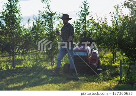 Farmer workingn in the middle of his orchard at sunset. Copy space. Farmer workingn in the middle of his orchard at sunset. Copy space. 127360685