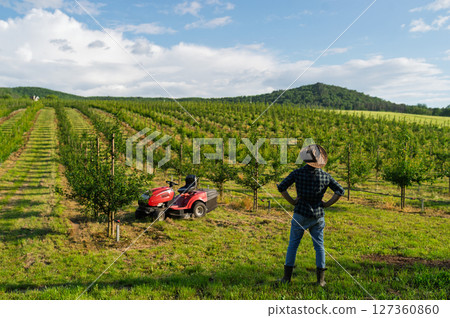 A mature farmer walking outdoors in orchard at sunset. Copy space. 127360860