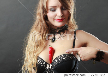 Woman wearing sexy lingerie holding chilli on chest Woman wearing sexy lingerie holding chilli on chest 127361334