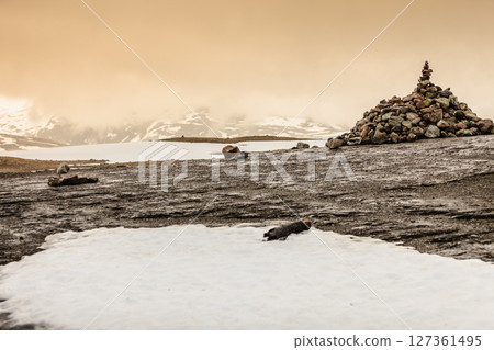 Stone stack and snowy mountains Norway 127361495
