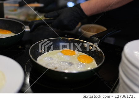 fried eggs with chives in an iron pan on a wooden table fried eggs with chives in an iron pan on a wooden table 127361725