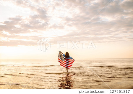 Young woman with American flag on beach. Patriotic holiday. Independence Day concept Young woman with American flag on beach. Patriotic holiday. Independence Day concept 127361817