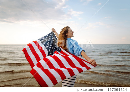 Young woman with American flag on beach. Patriotic holiday. Independence Day concept Young woman with American flag on beach. Patriotic holiday. Independence Day concept 127361824