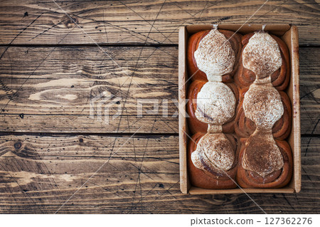 Kanelbulle Cinnamon buns with buttercream on a rustic wooden table. Homemade fresh pastries. top view, copy space. 127362276