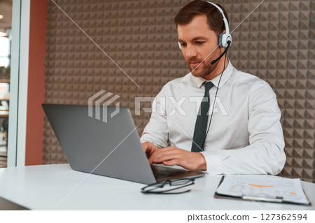 Using laptop. Handsome man in formal clothes is in the office Using laptop. Handsome man in formal clothes is in the office 127362594