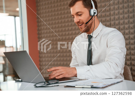 Using laptop. Handsome man in formal clothes is in the office 127362598