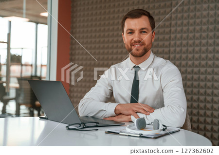 Handsome man in formal clothes is working by laptop in the office Handsome man in formal clothes is working by laptop in the office 127362602