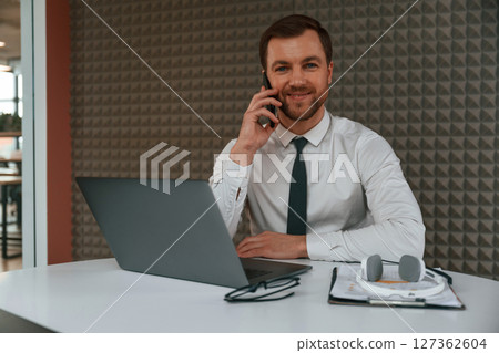 Handsome man in formal clothes is working by laptop in the office Handsome man in formal clothes is working by laptop in the office 127362604