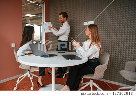 Manager is showing the plan project. Three business people are working in the office together 127362918