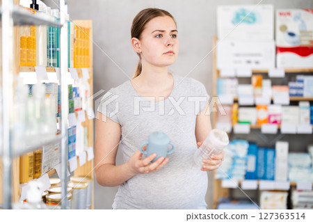 Pregnant woman are busy choosing baby feeding bottles at pharmacy Pregnant woman are busy choosing baby feeding bottles at pharmacy 127363514