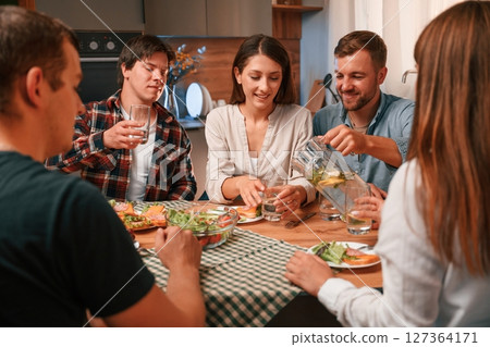 Delicious food. Group of people are on the kitchen, having dinner, spending time together Delicious food. Group of people are on the kitchen, having dinner, spending time together 127364171