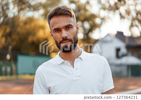 Beautiful portrait. Young man is on the tennis court at sunny daytime Beautiful portrait. Young man is on the tennis court at sunny daytime 127364231