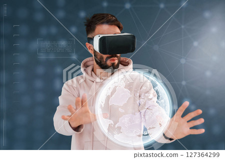 Image of Earth. In VR glasses. Handsome man is in the studio against blue background Image of Earth. In VR glasses. Handsome man is in the studio against blue background 127364299