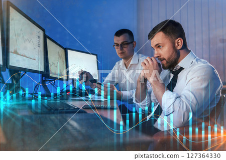 Graphs and data. Different information on screens. Two stock traders working in the office with exchange technology Graphs and data. Different information on screens. Two stock traders working in the office with exchange technology 127364330