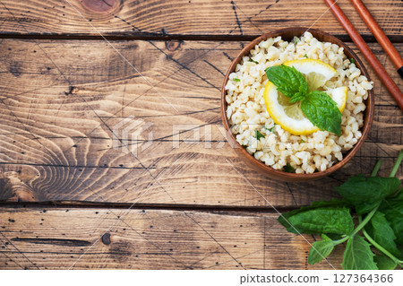 Boiled bulgur with fresh lemon and mint on a plate. A traditional oriental dish called Tabouleh. wooden background rustic top view, copy space Boiled bulgur with fresh lemon and mint on a plate. A traditional oriental dish called Tabouleh. wooden background rustic top view, copy space 127364366