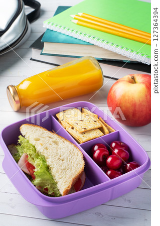 Delicious healthy sandwich in a lunch box, cookies and cherries. Take lunch with you to school or the office. Juice in a bottle and an apple. Delicious healthy sandwich in a lunch box, cookies and cherries. Take lunch with you to school or the office. Juice in a bottle and an apple. 127364394