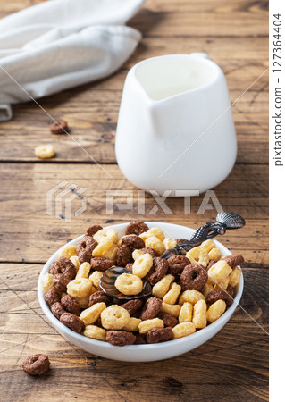 Dry breakfast cereals. Chocolate and corn rings made from natural cereals with milk in a plate. Wooden rustic background, copy space. Dry breakfast cereals. Chocolate and corn rings made from natural cereals with milk in a plate. Wooden rustic background, copy space. 127364404