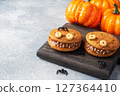 Cookies with cream paste in the shape of monsters for Halloween celebration. Funny homemade faces made of oatmeal cookies and boiled condensed milk. copy space 127364410