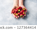 handful Juicy ripe strawberries in the hands on a concrete background. Sweet healthy dessert, vitamin harvest. copy space. 127364414