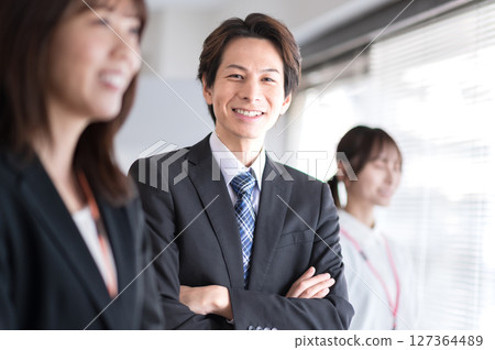 一名身著西裝、雙臂交叉的年輕男子 127364489