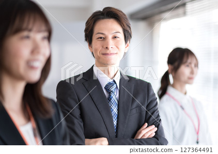 一名身著西裝、雙臂交叉的年輕男子 127364491