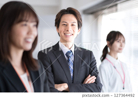 A young man in a suit with his arms folded 127364492