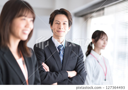 A young man in a suit with his arms folded 127364493