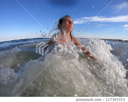 Powerful ocean waves splashing on child girl in summer vacation 127365353