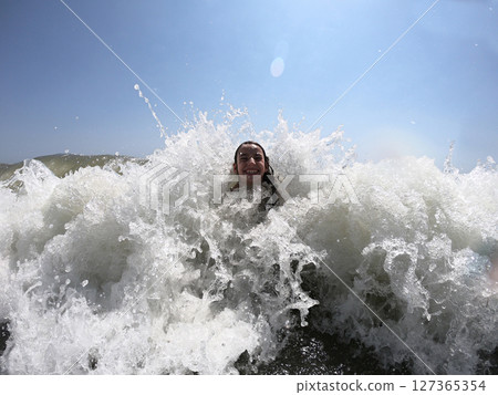 Powerful ocean waves splashing on child girl in summer vacation Powerful ocean waves splashing on child girl in summer vacation 127365354