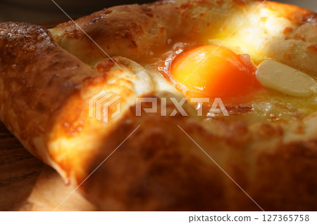 Closeup photo of Adjarian khachapuri, a traditional Georgian dish. A famous ethnic food from Georgia, popular in Caucasian cuisine and culinary tourism. 127365758